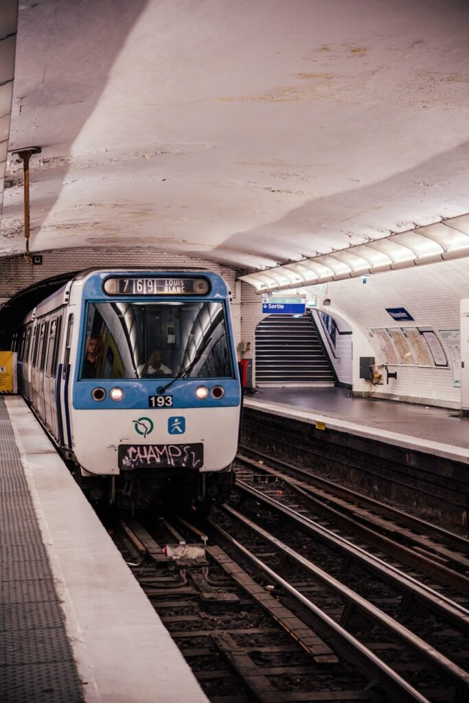Blue and white passenger train pulling into a railway station