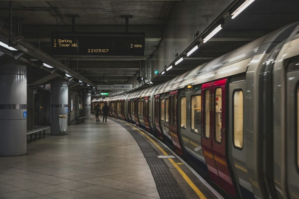 Metro train waiting at a station platform beside a digital arrival board